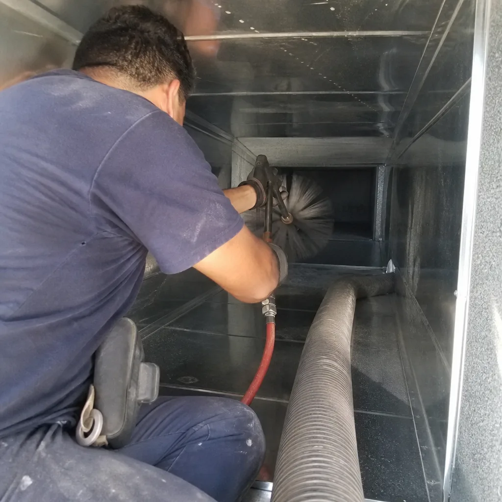 Technician using a rotating brush tool for professional air duct cleaning